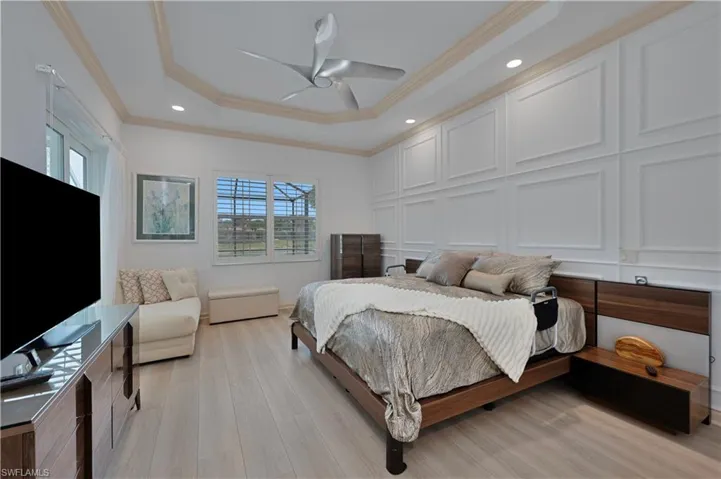 Bedroom featuring ornamental molding, a tray ceiling, light wood-type flooring, recessed lighting, and a ceiling fan