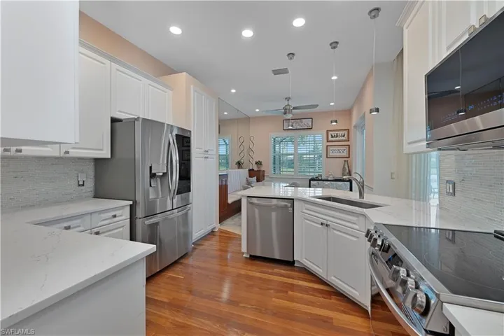 Kitchen featuring appliances with stainless steel finishes, a sink, light wood-style floors, a ceiling fan, and white cabinets