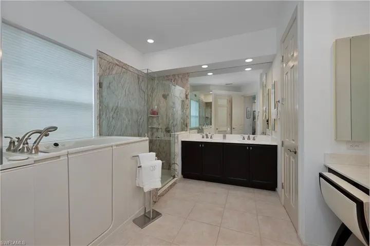 Full bath with tile patterned floors, a marble finish shower, a garden tub, vanity, and recessed lighting