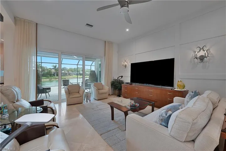Living room with a ceiling fan, recessed lighting, a decorative wall, and light tile patterned floors