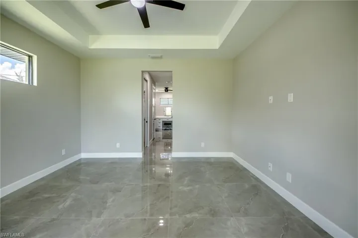 Master Bedroom with Trey Ceilings, Transom Window, featuring tile patterned floors, ceiling fan, and a tray ceiling