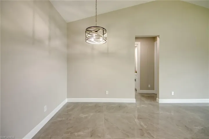 Empty room featuring tile patterned floors, a chandelier, and high vaulted ceiling