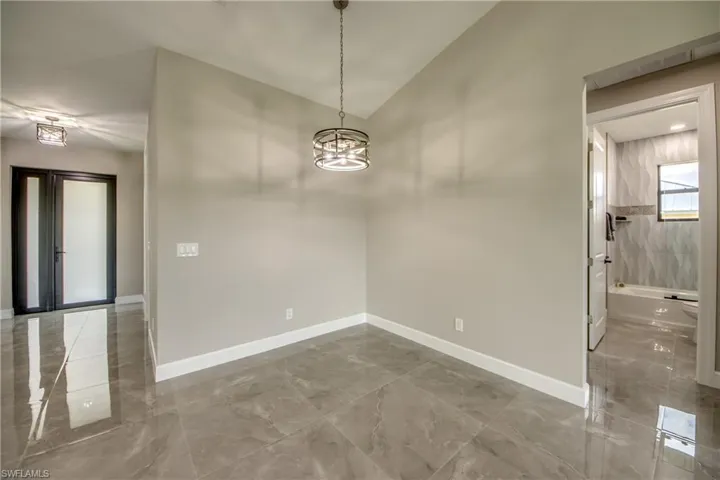 Tiled spare room with an inviting chandelier