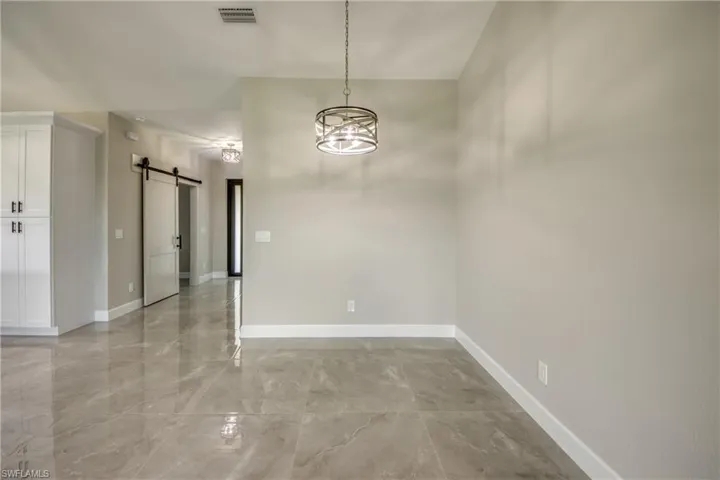 Empty room featuring light tile patterned flooring and a barn door