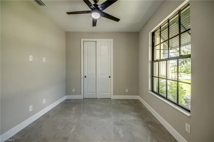 Unfurnished bedroom with a closet by Front Entry, could be office/den tile patterned flooring, and ceiling fan