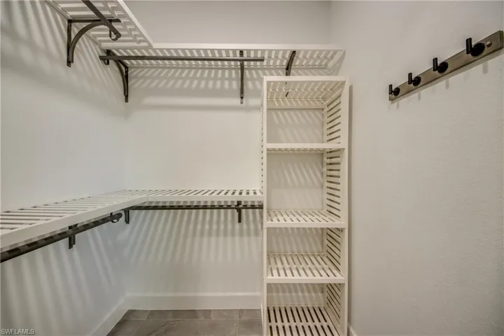 HIS AND HERS Spacious MASTER closet with tile patterned floors, CUSTOM WOOD SHELVING AND REAL BARS TO HANG YOUR CLOTHES ON!