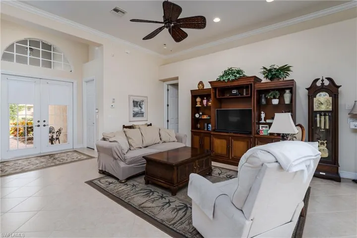 Living room featuring french doors, crown molding, a ceiling fan, and light tile patterned floors