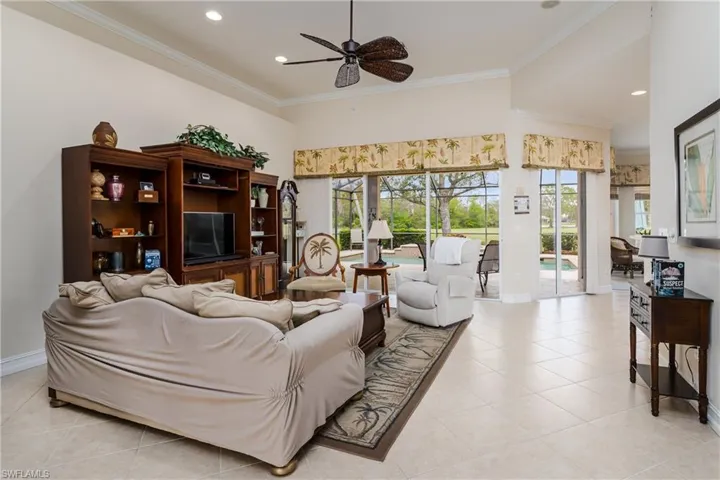 Living area with a ceiling fan, ornamental molding, light tile patterned floors, a high ceiling, and recessed lighting