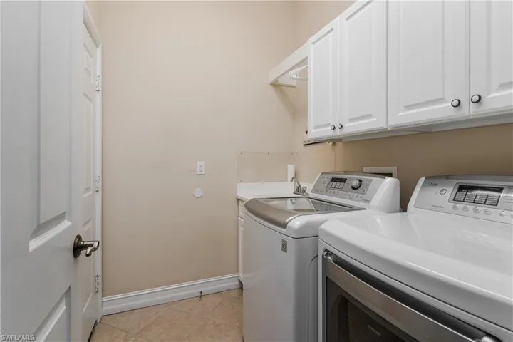 Laundry area with cabinet space, washer and clothes dryer, and light tile patterned flooring