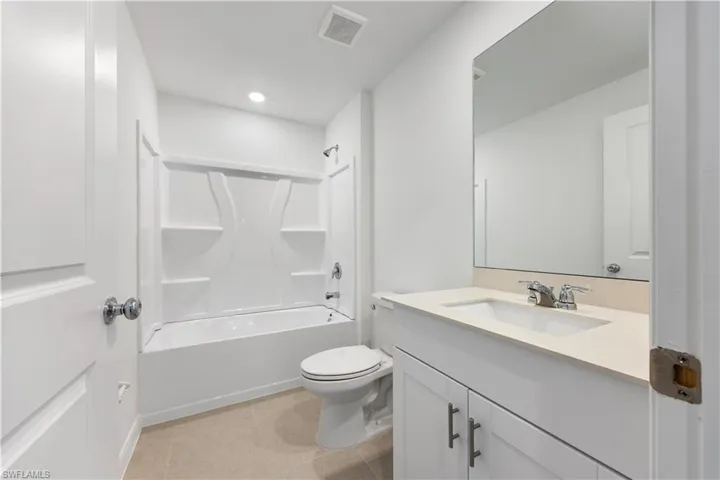 Bathroom with vanity, shower / tub combination, and light tile patterned floors