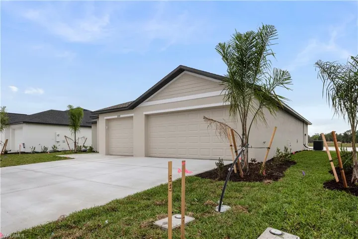 View of side of home with driveway, a yard, an attached garage, and stucco siding