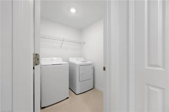 Laundry room with washer and clothes dryer and light tile patterned floors