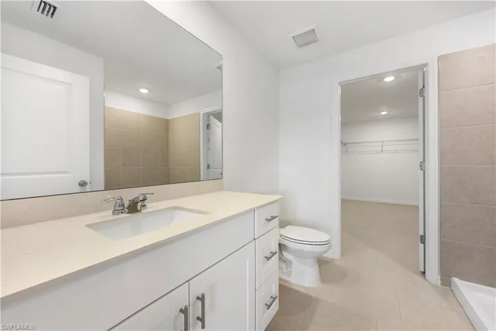 Full bath featuring vanity, a spacious closet, light tile patterned floors, and recessed lighting