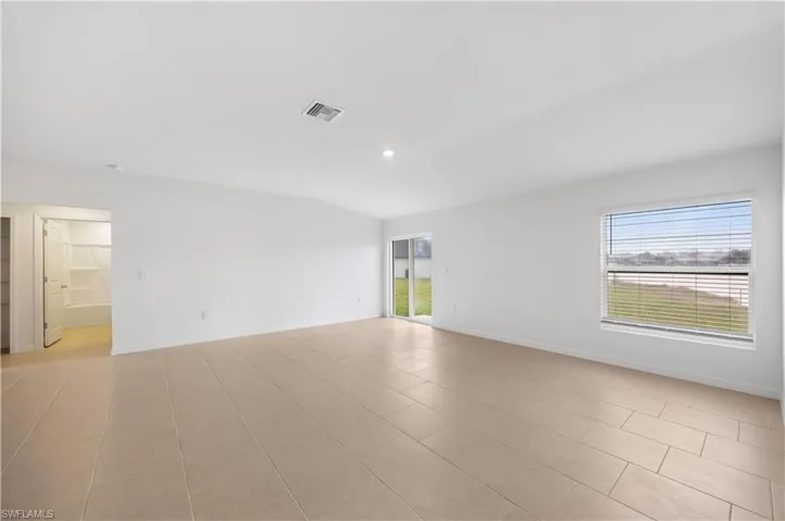 Spare room featuring vaulted ceiling, light tile patterned floors, and recessed lighting