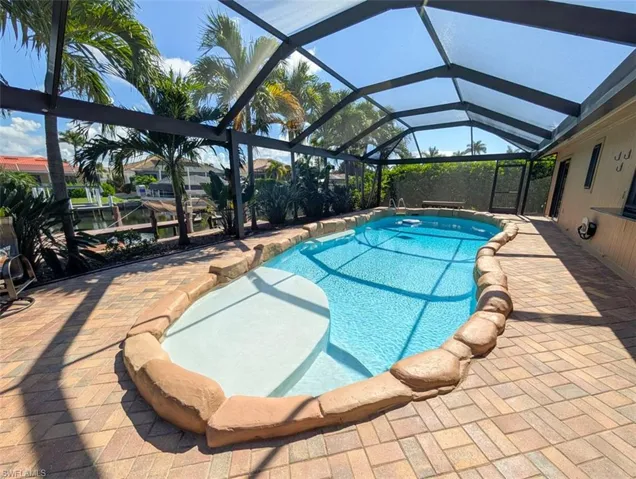 Swimming pool with a sunroom, glass enclosure, and a patio