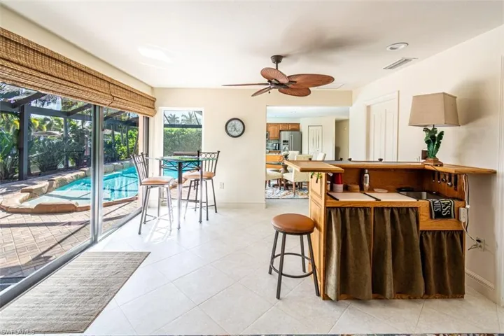 Kitchen with a kitchen breakfast bar, a sunroom, light tile patterned floors, a ceiling fan, and stainless steel fridge with ice dispenser