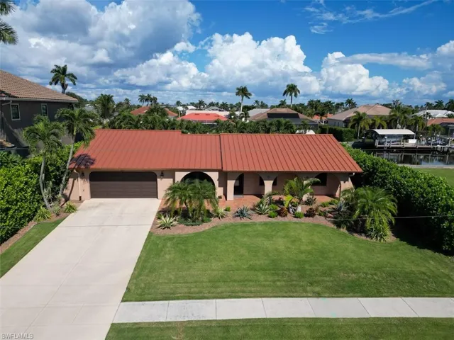 Mediterranean / spanish-style home featuring stucco siding, an attached garage, driveway, a front lawn, and a residential view