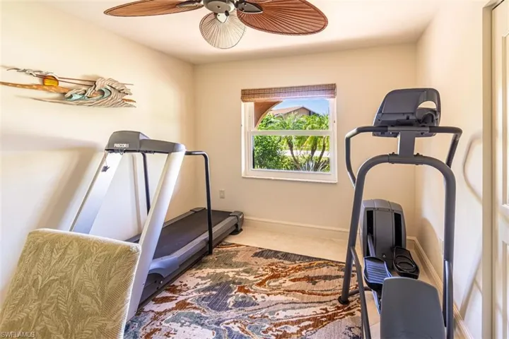 Workout room with ceiling fan and light carpet