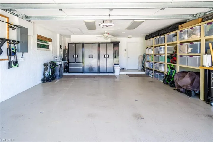 Garage with electric panel, ceiling fan, and water heater