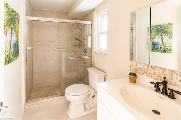 Bathroom with vanity, backsplash, a shower stall, and tile patterned flooring