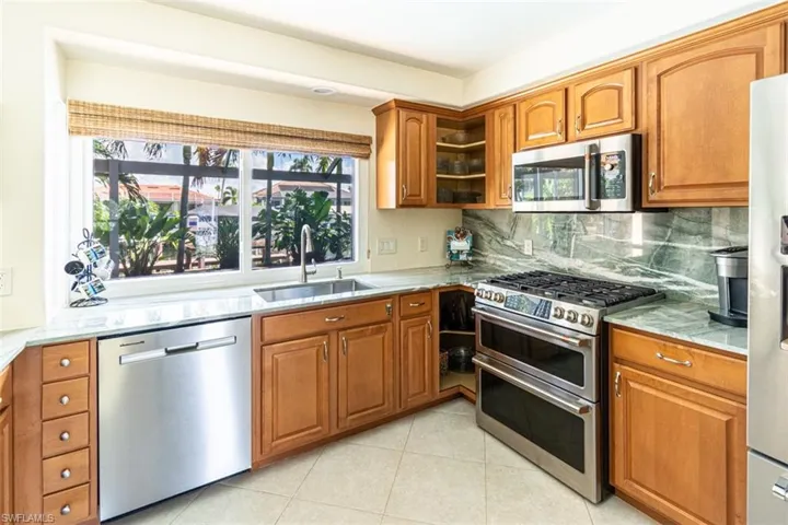 Kitchen featuring appliances with stainless steel finishes, brown cabinets, backsplash, and healthy amount of natural light
