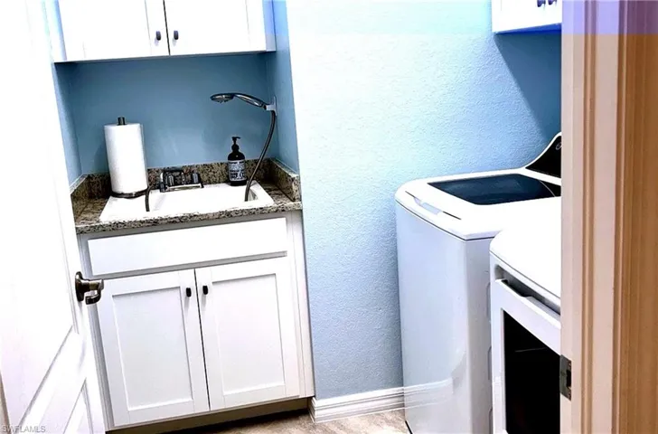 Laundry area featuring a textured wall, independent washer and dryer, and cabinet space