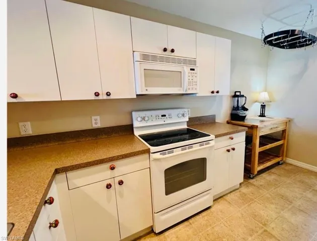 Kitchen with white appliances, white cabinets, and dark countertops