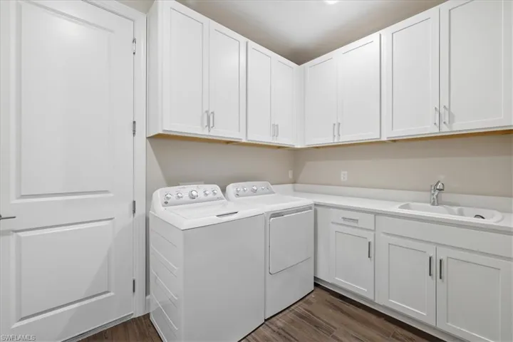 Well-appointed laundry area featuring white cabinetry and wood-finish flooring