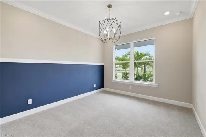 Room featuring two-tone walls with a dark blue lower section and neutral upper section, complemented by white crown molding and baseboards