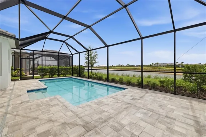 Screened lanai featuring a rectangular swimming pool with integrated steps, paver decking, and landscaping