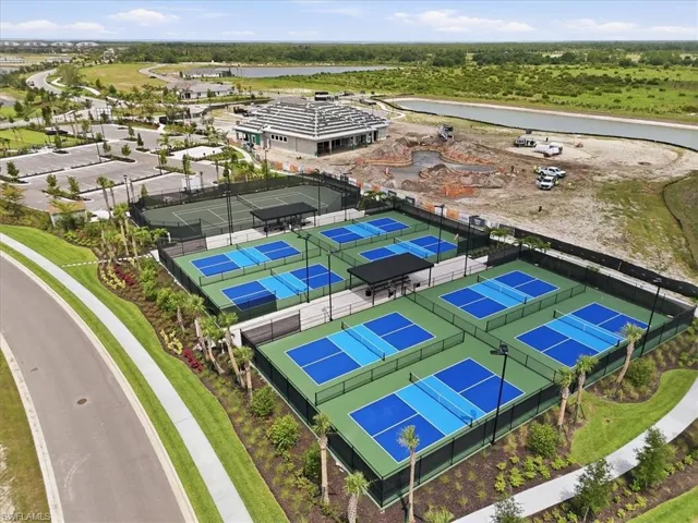 Multiple outdoor courts, including six pickleball courts and two tennis courts, featuring dark fencing, light poles, and surrounding landscaping