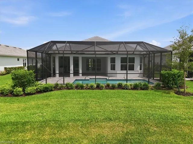 Rear exterior featuring a screened-in pool area, paver patio, and sliding glass doors