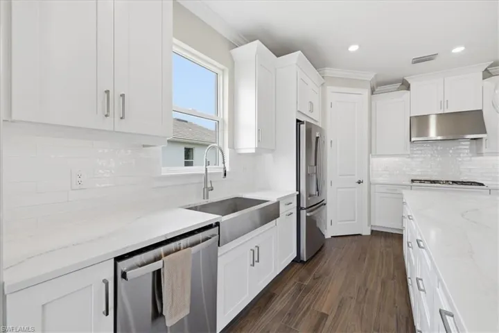 Modern kitchen featuring white shaker cabinetry, white subway tile backsplash, and wood-finish flooring