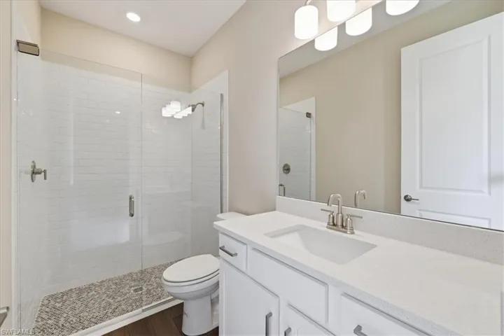 Modern bathroom featuring a glass-enclosed shower with subway tile surround and pebble-style flooring