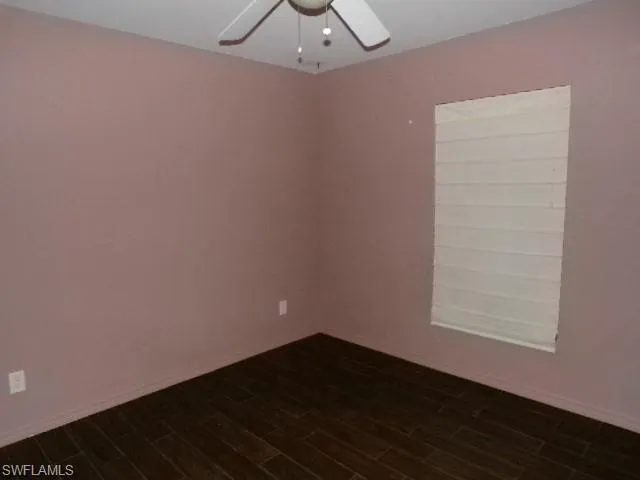 Empty room featuring dark wood-style floors and ceiling fan
