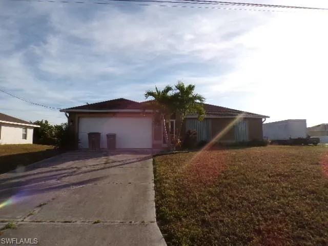 View of front of home with concrete driveway, an attached garage, and a front lawn