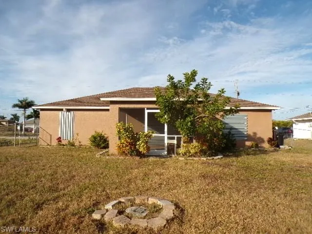 Rear view of house with a fire pit, stucco siding, and a sunroom