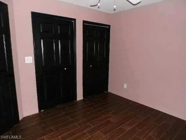 Unfurnished bedroom featuring two closets, ceiling fan, and wood finish floors