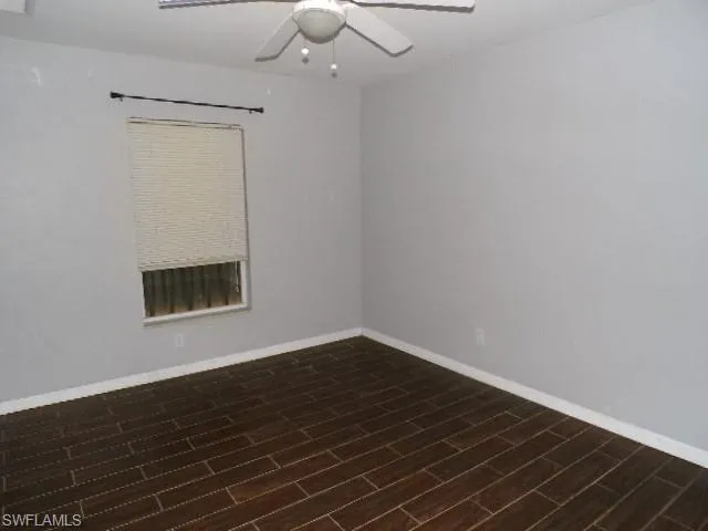 Spare room with dark wood-type flooring and ceiling fan