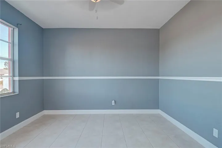 Empty room with ceiling fan and light tile patterned floors