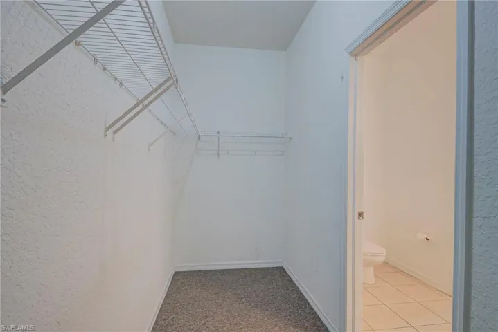 Walk in closet with light colored carpet and light tile patterned floors