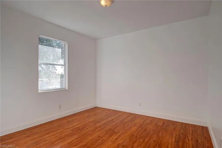 Unfurnished room with wood finished floors and baseboards