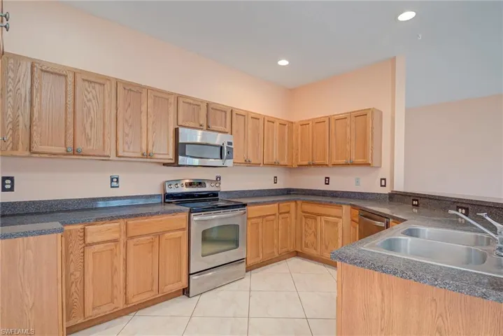 Kitchen with stainless steel appliances, light tile patterned floors, recessed lighting, and a peninsula