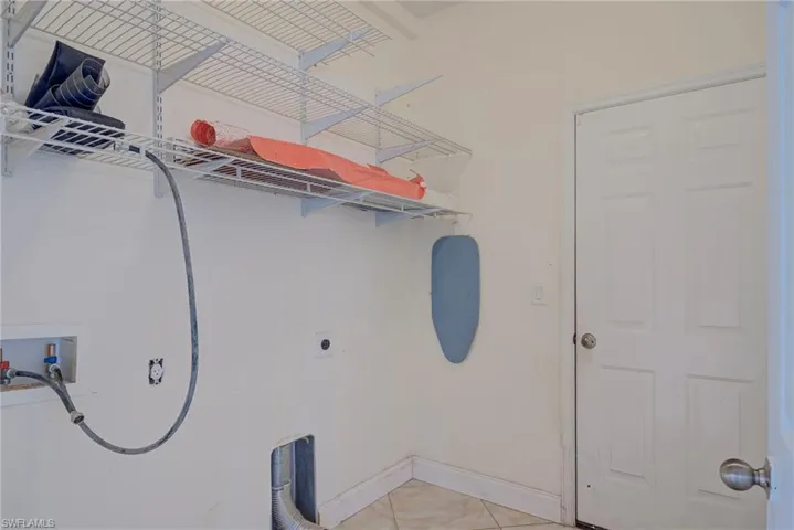 Laundry area with washer hookup, hookup for an electric dryer, and light tile patterned flooring