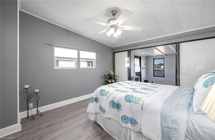 Bedroom with hardwood / wood-style floors, ornamental molding, ceiling fan, and lofted ceiling