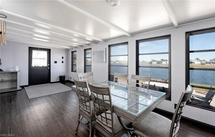 Dining area featuring dark hardwood / wood-style floors, beam ceiling, a water view, and a textured ceiling