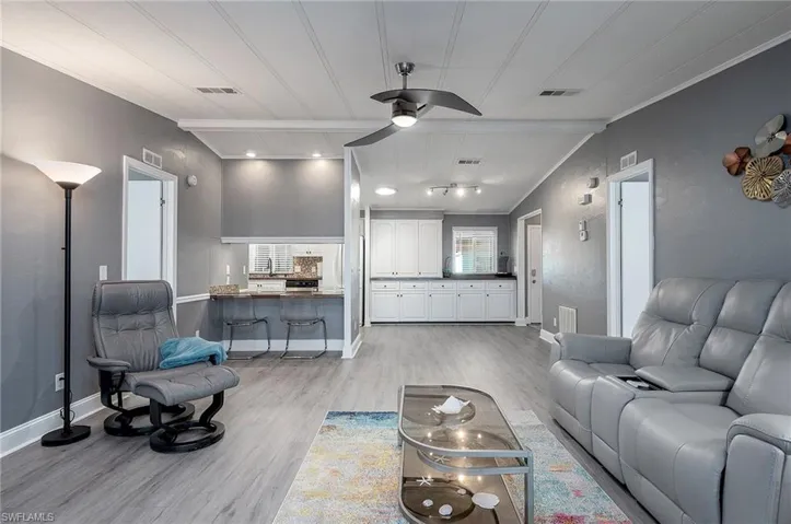 Living room with crown molding, light hardwood / wood-style flooring, ceiling fan, and lofted ceiling