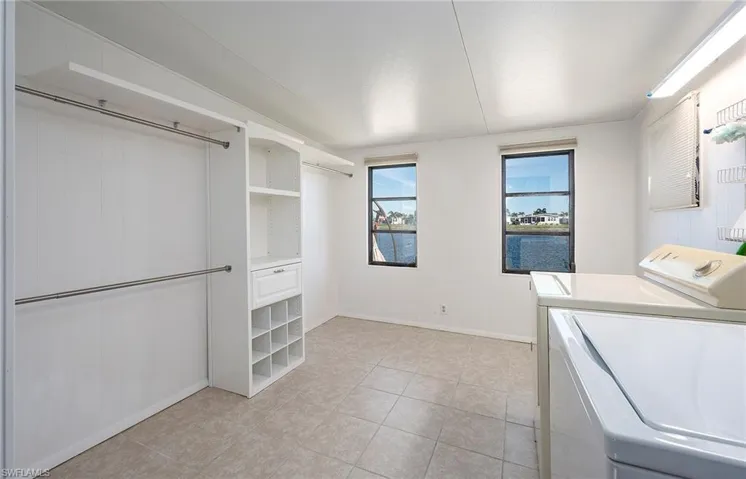 Clothes washing area with light tile patterned floors and washing machine and clothes dryer