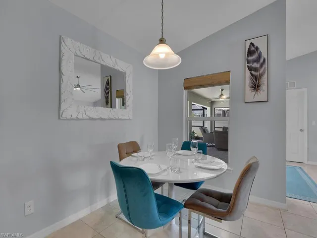 Dining room with lofted ceiling, ceiling fan, and light tile patterned floors