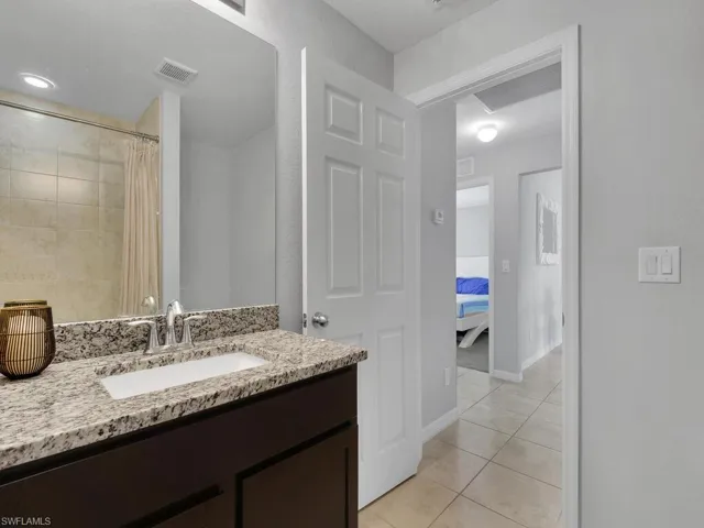 Bathroom with vanity, walk in shower, and tile patterned flooring